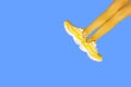 New Yellow female sneakers on long woman legs in yellow tights isolated on blue background Royalty Free Stock Photo