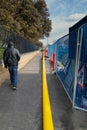 New yellow gas pipe stretched along a pavement as it is being fed underground. A pedestrian is