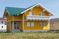 New yellow house with white windows and a large wooden balcony built in the village Royalty Free Stock Photo