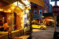 Street scene with restaurant, lights, and people at night seen from Greenwich Village, West Village Manhattan.