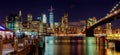 New York City Brooklyn Bridge and Manhattan skyline with skyscrapers over Hudson River illuminated lights at dusk after sunset. Royalty Free Stock Photo