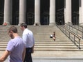 Two men walking past people sitting on the front steps of the beautiful United States Post Office on 8th Avenue in New York City Royalty Free Stock Photo