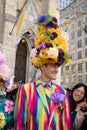 Man in a towering floral hat and colorful striped suit at Easter Bonnet Parade