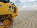 New York City Parks John Deere yellow excavator on broad sandy beach