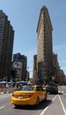 New York City, USA: Flatiron Building with Yellow Taxicab Passing Royalty Free Stock Photo