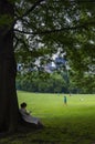 Young woman reading a book under a tree at the Central Park with the New York skyline in the background, in the city of New York, Royalty Free Stock Photo