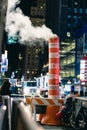 New York, New York - November 16, 2018 : Vapor riding from a manhole in Manhattan through white and orange steam chimneys