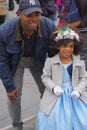 A Yankees fan and little girl in a blue dress and flowered bonnet pose for pictures at the Fifth Avenue Easter Parade.