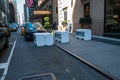 Large white concrete barricades used by the New York Police Department for crowd and traffic control on the street and sidewalk