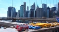 New York, NY, USA. Skyline of Manhattan skyscrapers from the Brooklyn Bridge. Toys for sale police car, school bus, yellow taxi