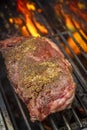 New York strip steak with dry rub on bbq with flames in background Royalty Free Stock Photo