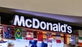 Row of small national flags of different countries under a large sing of McDonald`s restaurant