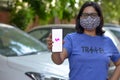 New York, USA, 2020. Girl wearing mask showing Lyft app on her mobile phone screen while standing in front of her fleet of cars.