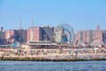 Crowded Coney Island beach and amusement parks seen from the pier on a sunny day.