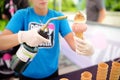 New York, USA - July 9, 2019: Seller is toasting giant scoop of marshmallow on top cone of ice cream on street of New York.