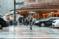 New York, USA - June 17, 2017: A woman tourist with backback and an umbrella crossing the road of busy downtown