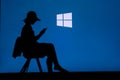 NEW YORK, USA, 25. MAY 2020: Microsoft Windows graphical operating system Young woman silhouette sitting on chair and playing on