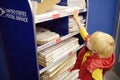 NEW YORK, USA - 23 OCTOBER 2018: Little boy at the post office chooses an packaging - envelope / box for mailing