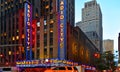 New York USA, urban classic building, colors and neon lights of Radio City Music Hall in Manhattan with urban traffic and yellow t Royalty Free Stock Photo
