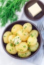 New young boiled  potato topped with melted butter and chopped dill in ceramic bowl, vertical,  top view Royalty Free Stock Photo