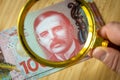 New Zealand money, 100 dollar banknote spread out on the table, magnifying glass lying down, financial and business concept