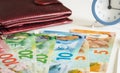 New Zealand dollars next to the wallet and the clock showing five to twelve Royalty Free Stock Photo