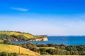 New Zealand iconic landscape - lush green hills and cliff over blue sea.