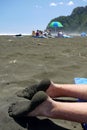 New Zealand: sandy feet on black sand beach Royalty Free Stock Photo