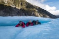 Group of travellers laying under a ice arch at Fox Glacier in New Zealand