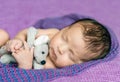 Newborn baby asleep on a purple blanket