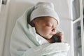 Newborn baby asleep, swaddled in hospital blanket and wearing a hat Royalty Free Stock Photo