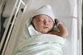 Newborn baby asleep, swaddled in hospital blanket and wearing a hat Royalty Free Stock Photo