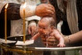 Newborn baby baptism in Holy water. baby holding mother`s hands. Infant bathe in water. Baptism in the font Royalty Free Stock Photo