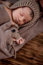 Newborn baby, beautiful infant lies and holding a tiny teddy bear in the bed on wooden background Royalty Free Stock Photo