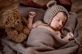 Newborn baby, beautiful infant lies and holding a tiny teddy bear in the bed on wooden background Royalty Free Stock Photo