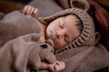 Newborn baby, beautiful infant lies and holding a tiny teddy bear in the bed on wooden background Royalty Free Stock Photo