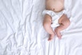 Newborn baby belly and legs in diaper, lying on white bed, top view, copy space Royalty Free Stock Photo