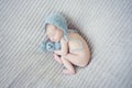 Newborn baby with knitted toy and cap sleeping on blanket Royalty Free Stock Photo