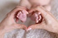 Newborn or Baby born. New Mom or mother doing Heart with fingers. Child or kid feet in mother hand. Barefoot baby. Royalty Free Stock Photo