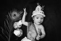 newborn baby boy in krishna dressed with props from unique perspective in black and white