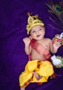 newborn baby boy in krishna dressed with props from unique perspective in different expression