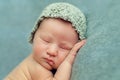 Newborn baby boy sleeping in the fetal position on a blue background, Face closeup Royalty Free Stock Photo