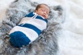 Newborn baby boy sleeping and swaddled in a knit wrap on bed Royalty Free Stock Photo