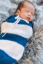 Newborn baby boy sleeping and swaddled in a knit wrap  on bed Royalty Free Stock Photo