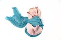 Newborn baby boy in turquoise wrap against white