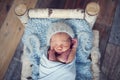 Newborn baby boy wrapped in blue wrap and wool cap sleeping in the birch bed. Bed on vintage retro wood floor background, Royalty Free Stock Photo