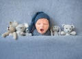 Newborn baby boy yawning and lying between plush toys Royalty Free Stock Photo