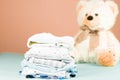 Newborn baby clothes laundry washed, ironed and stacked on pink background with a teddy bear Royalty Free Stock Photo