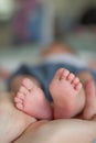 Newborn baby cradled in the hands of an adult, lying on a white bed