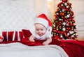 Newborn baby creeps on bed, wearing Santa hat. Baby in a Christmas Santa cap Royalty Free Stock Photo